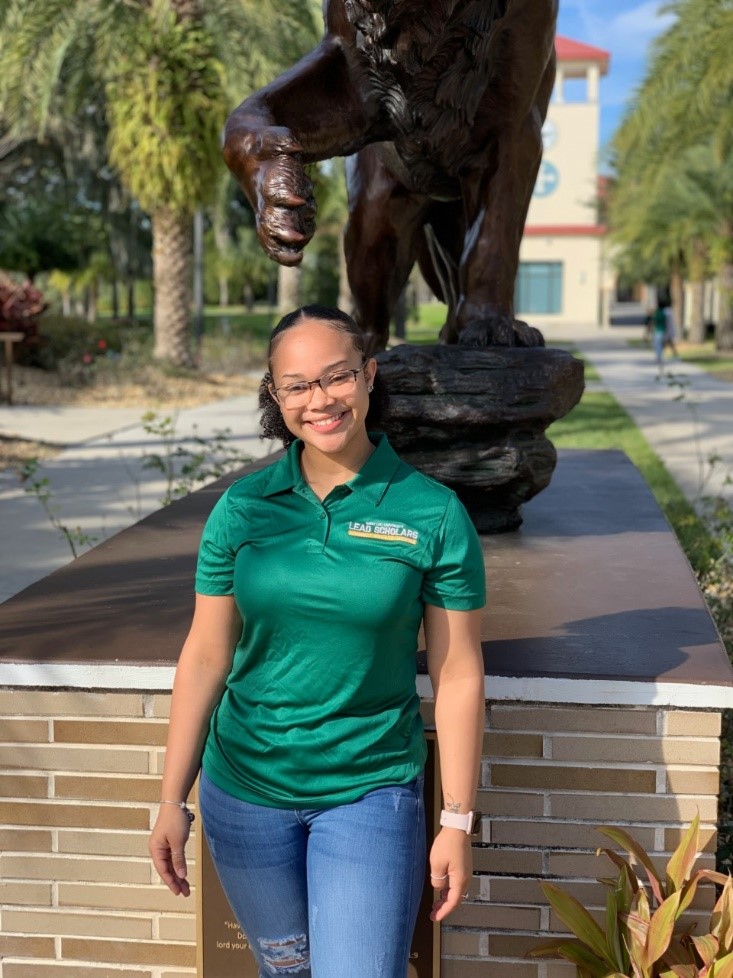 A photo of Tracey Sands, a student in Saint Leo University's 3+1 Marketing to MBA accelerated degree program, standing in front of the lion statue on University Campus A photo of Tracey Sands, a student in Saint Leo University's 3+1 Marketing to MBA accelerated degree program, standing in front of the lion statue on University Campus