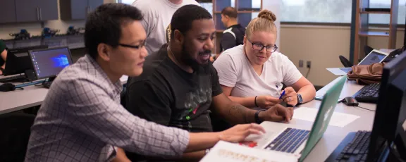 Professor speaks with students in the cybersecurity lab